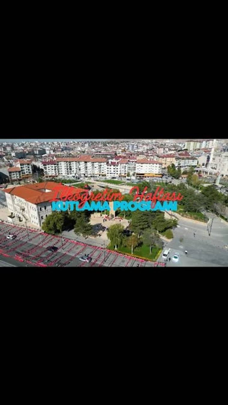 Havadan görünümde, kent içindeki okul binası ve çevresinde “İlköğretim Haftası Kutlama Programı” yazısı yer alıyor.