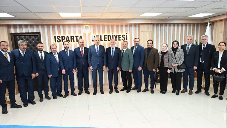 Isparta Belediyesi binasında, çeşitli kişiler bir arada poz veriyor.