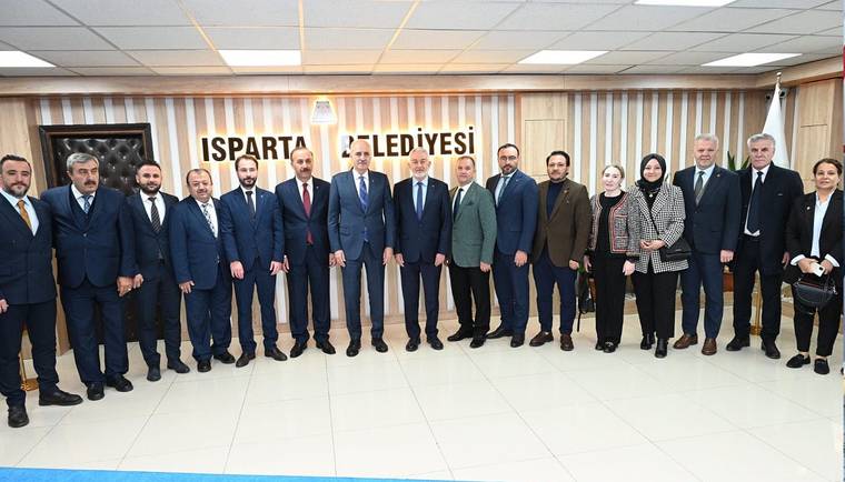 Isparta Belediyesi binasında, çeşitli kişiler bir arada poz veriyor.
