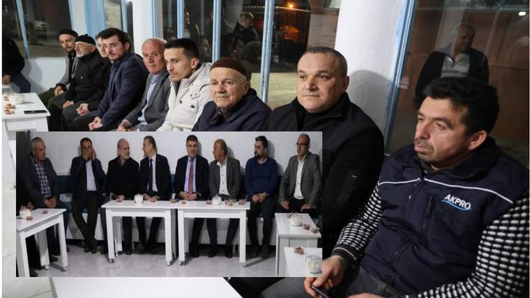 Kapalı bir mekânda oturan erkekler, beyaz masaların çevresinde sohbet ederken görülüyor.