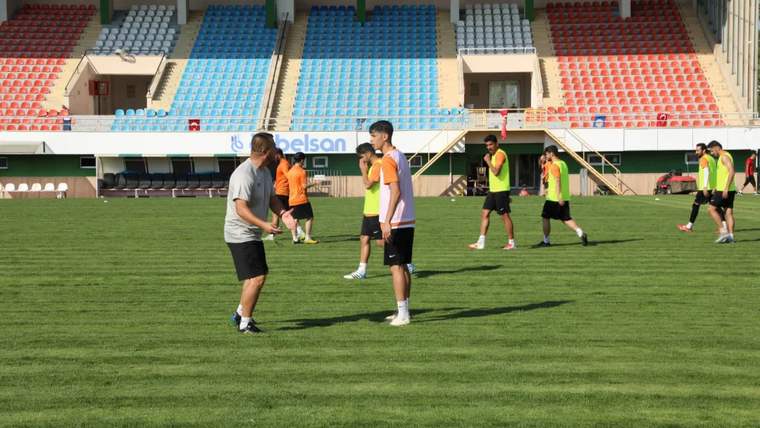Futbol sahasında antrenman yapan oyuncular, teknik ekip ile birlikte çalışıyor.