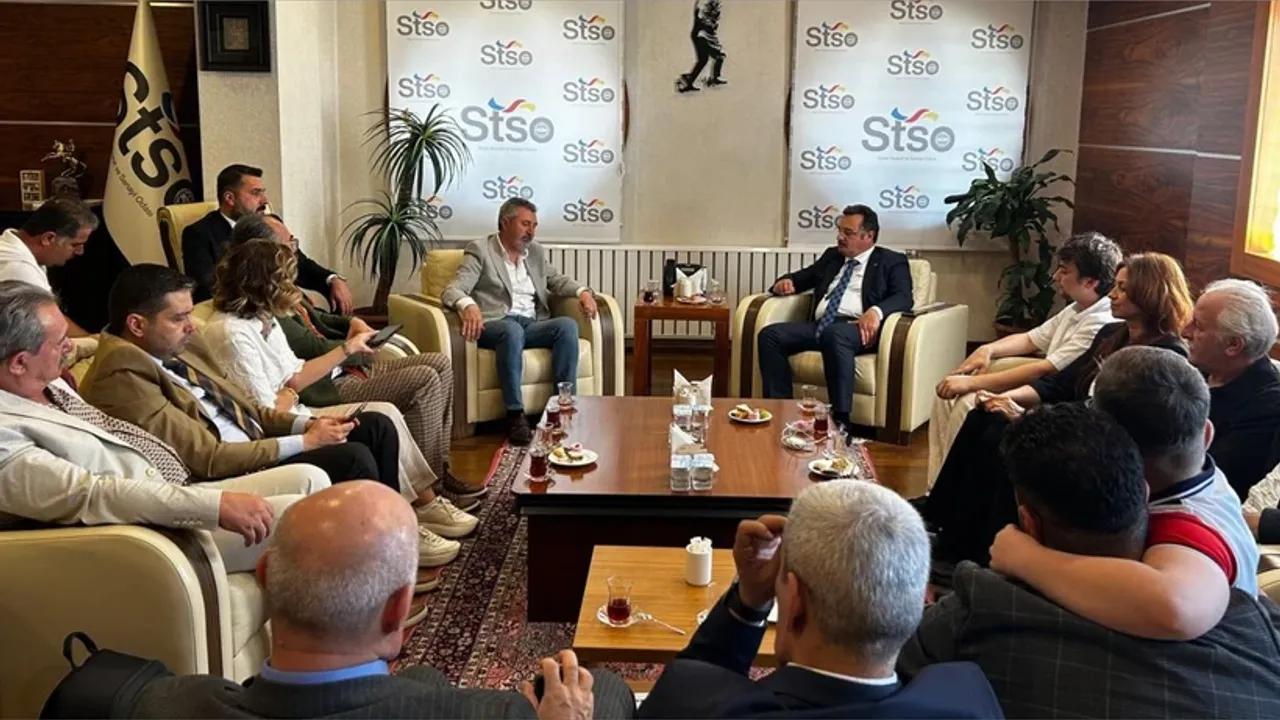 STSO logolu panonun önünde, koltuklarda oturan bir grup kişi salondaki toplantıda karşılıklı konuşuyor.