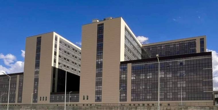 Cam cepheli, çok katlı büyük bir bina, mavi gökyüzü altında açık alanda görüntüleniyor.