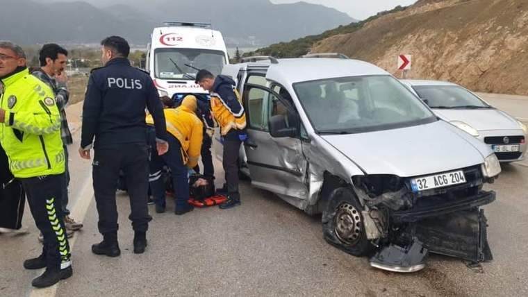 Hasarlı bir minibüsün yanında polis ve sağlık görevlileri, bir kişiye yardım ederken görülüyor.