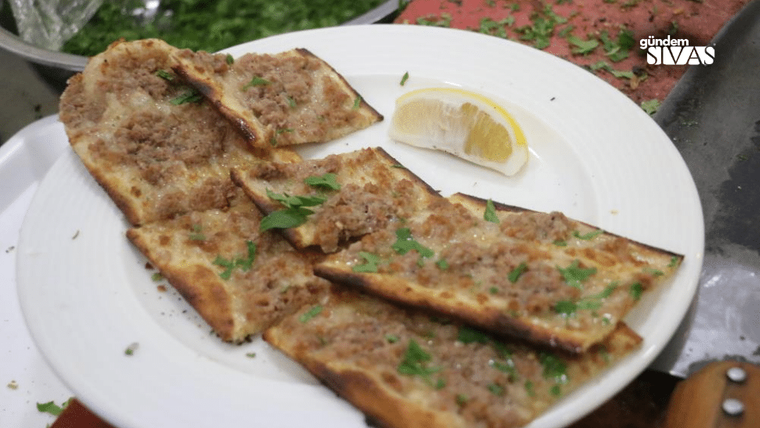 Dört dilim etli ekmek, tabakta limon dilimi ve yeşillik ile birlikte sunulmuş.