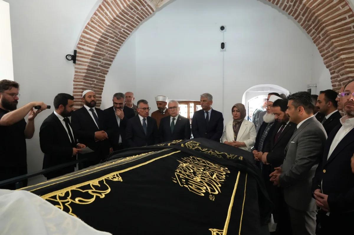 Şems-i Sivasî'nin türbesinde bir grup insan, türbe örtüsünün etrafında toplanmış.