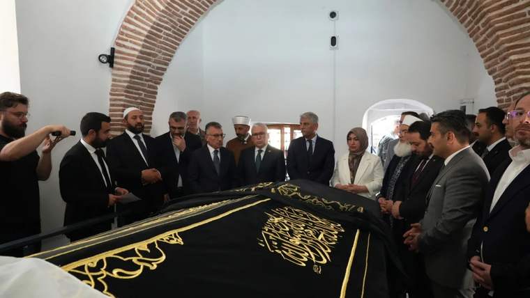 Şems-i Sivasî'nin türbesinde bir grup insan, türbe örtüsünün etrafında toplanmış.