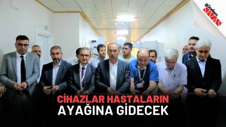 Hastane koridorunda, aralarında sağlık çalışanlarının da bulunduğu bir grup insan yan yana duruyor.