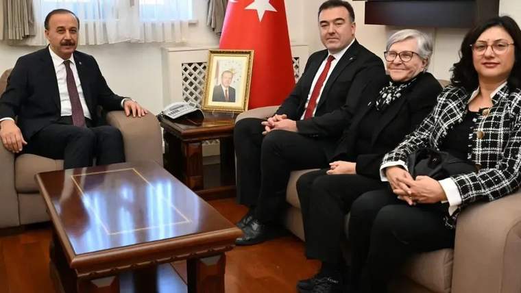 Isparta Valisi Abdullah Erin, koltukta otururken, yanında üç kişiyle birlikte bir odada görüntüleniyor.