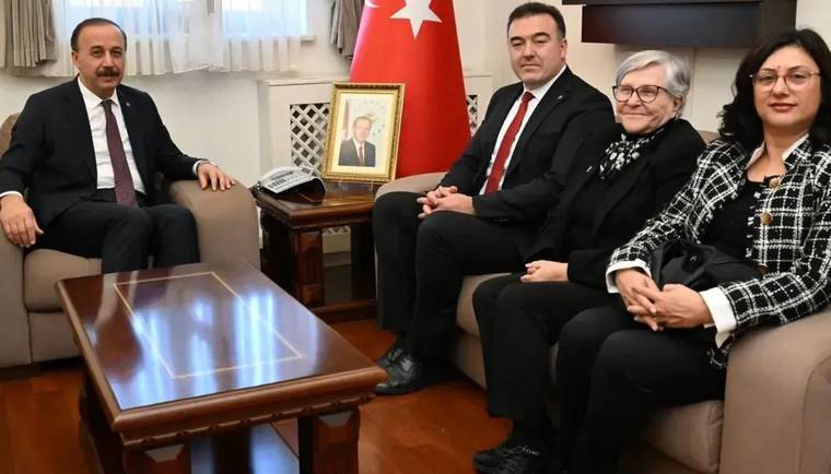 Isparta Valisi Abdullah Erin, koltukta otururken, yanında üç kişiyle birlikte bir odada görüntüleniyor.