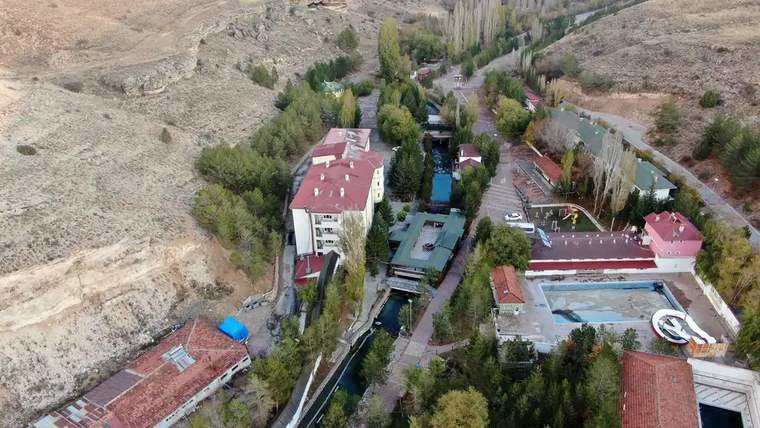 Kangal Balıklıgöl bölgesinin havadan görünümü, yeşil ağaçlar ve binalar yer alıyor.