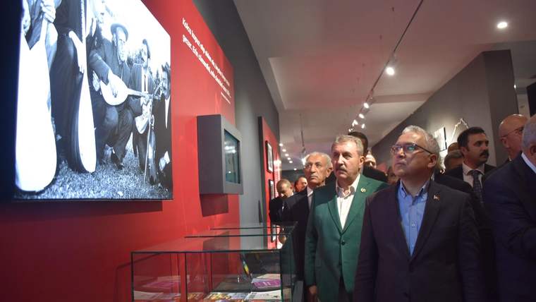 Müzede, Aşık Veysel'in fotoğrafının bulunduğu bir duvarın önünde birkaç kişi duruyor.