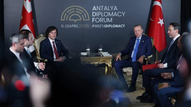 Antalya Diplomasi Forumu yazılı salonda, iki heyet karşılıklı koltuklarda otururken ortada iki kişi görülüyor.