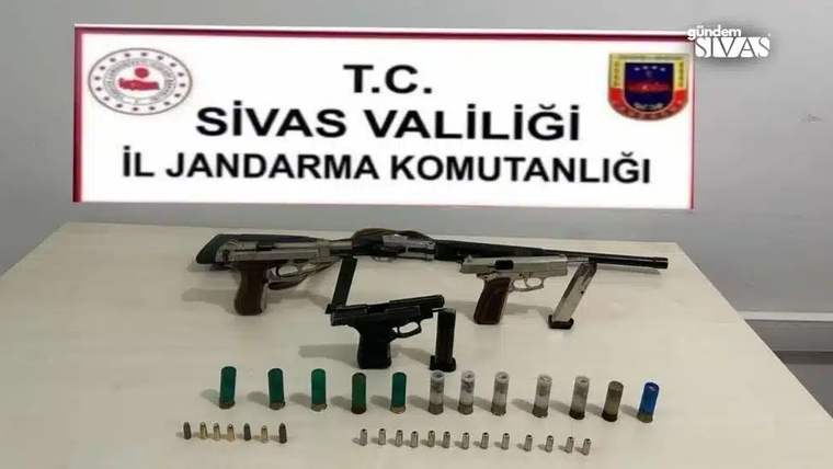 Sivas İl Jandarma Komutanlığı tabelası önünde üç tabanca, bir tüfek ve çeşitli mermiler sergileniyor.