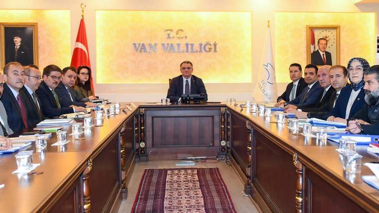 Van Valiliği yazılı salonda, uzun toplantı masası çevresinde oturan kişiler ve masanın başında bir kişi görülüyor.