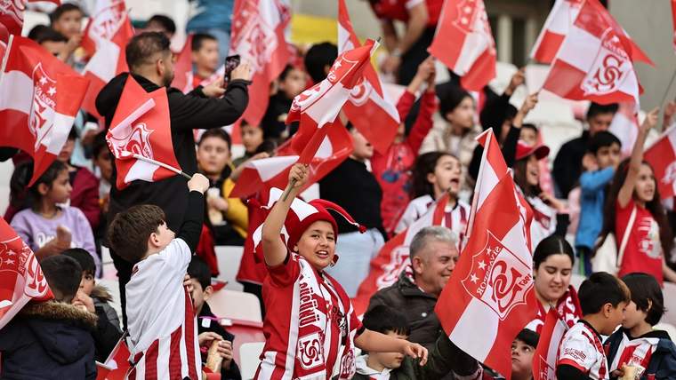 Sivasspor taraftarları, stadyumda kırmızı-beyaz bayraklar sallayarak coşkulu bir şekilde destek veriyor.