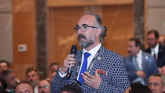 Mikrofonu elinde tutan bir kişi, toplantıda konuşma yapıyor.