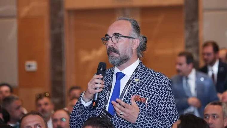 Mikrofonu elinde tutan bir kişi, toplantıda konuşma yapıyor.