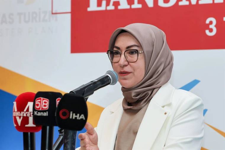 Kürsüde konuşan bir kadın, mikrofonun önünde açıklama yapıyor.