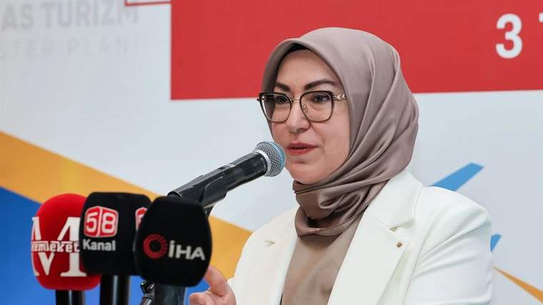 Kürsüde konuşan bir kadın, mikrofonun önünde açıklama yapıyor.