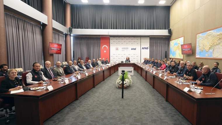 AFAD binasında, uzun bir masanın etrafında oturan kalabalık bir grup, toplantı yapıyor.