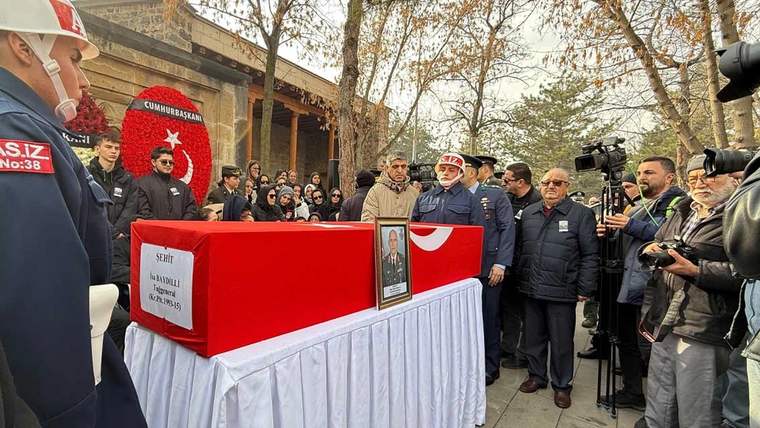 Kırmızı bir tabutun önünde, kalabalık bir grup insan ve güvenlik güçleri yer alıyor.