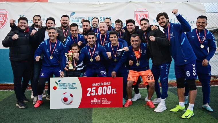 Madalyalı futbolcular, kupayla birlikte halı saha üzerinde 25.000 TL yazılı ödül panosunun önünde poz veriyor.