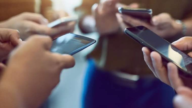 Bir grup insan, ellerinde akıllı telefonlarla etkileşimde bulunuyor.