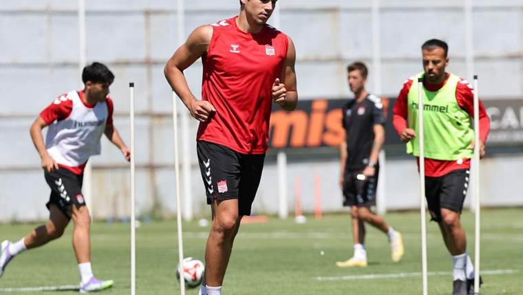 Antrenman yapan futbolcular, sahada koşu yapıyorlar.