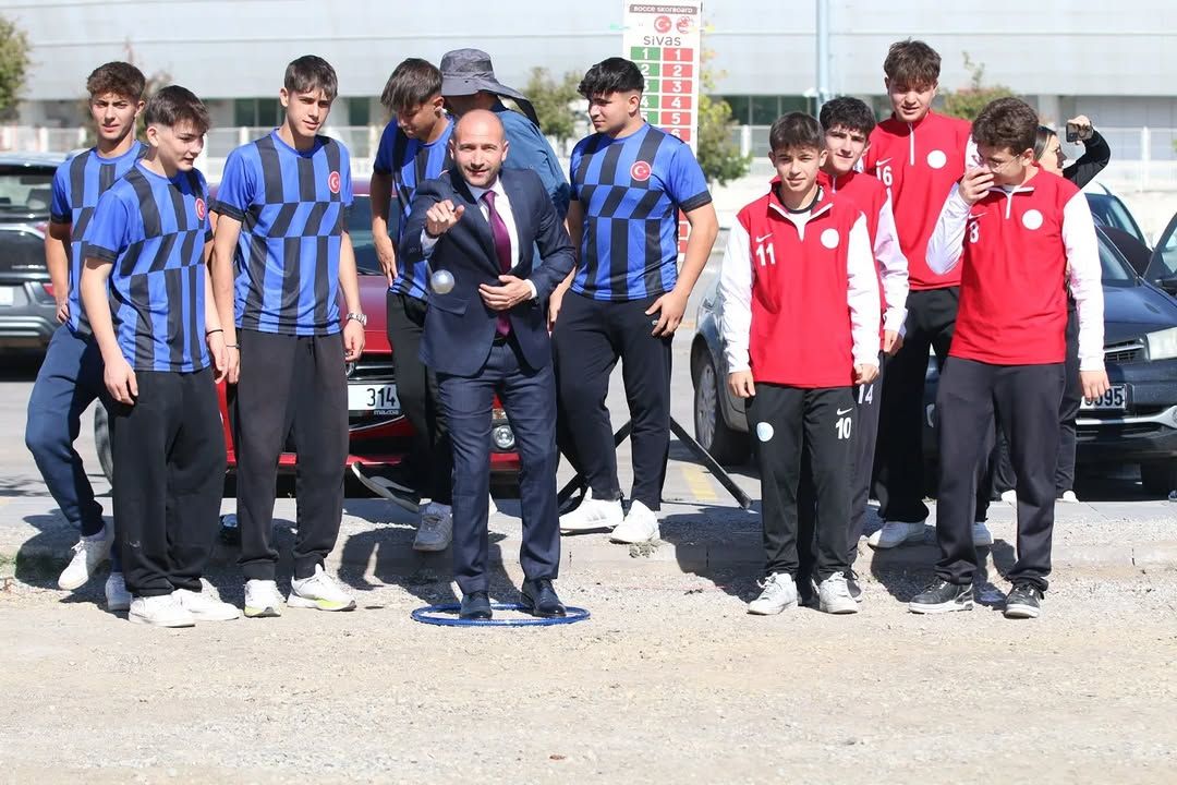 Bocce oynayan bir kişi, etrafında genç sporcular kalabalığı var.