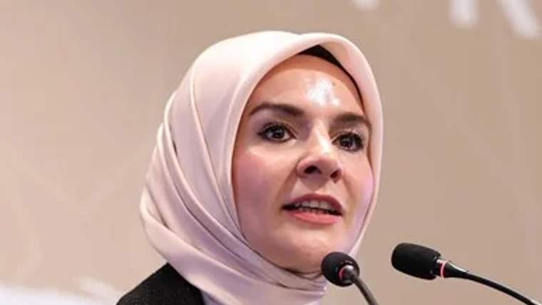 Kürsüde konuşan bir kişi, mikrofonlara doğru yönelmiş.