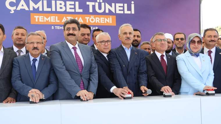 Temel atma töreninde düğmeye basan yetkililer, arka planda kalabalık bir grup yer alıyor.