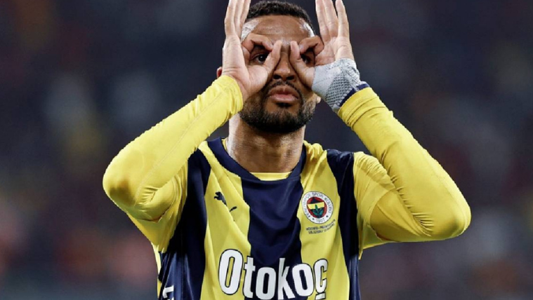 Fenerbahçe forması giymiş bir futbolcu, elleriyle gözlük yaparak poz veriyor.