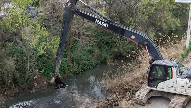 Bir iş makinesi, Güzelköy Deresi'nde suyun içindeki atıkları temizliyor.
