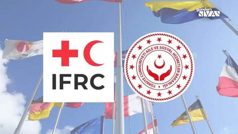 Gökyüzü önünde Türk Kızılayı ve IFRC logolarının bulunduğu panolar, çevrelerinde dalgalanan bayraklar
