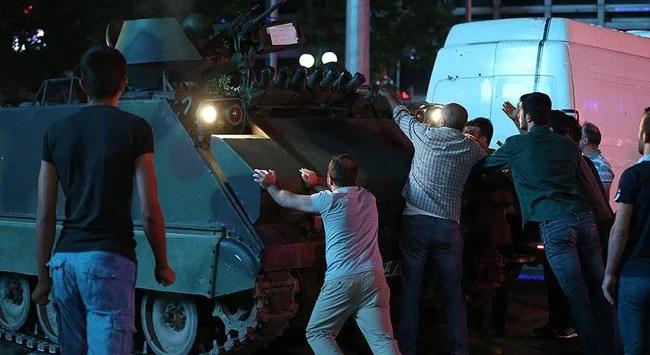 Bir grup insan, bir askeri aracı itmeye çalışıyor.