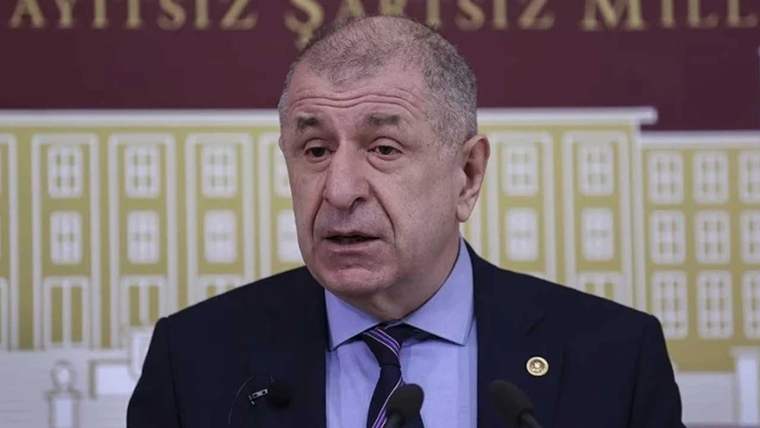 Kürsüde konuşan bir kişi, arka planda sarı ve kırmızı renkli bir duvar var.