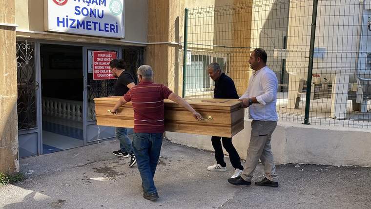 Dört kişi, bir tabutu bir binanın girişine taşıyor.