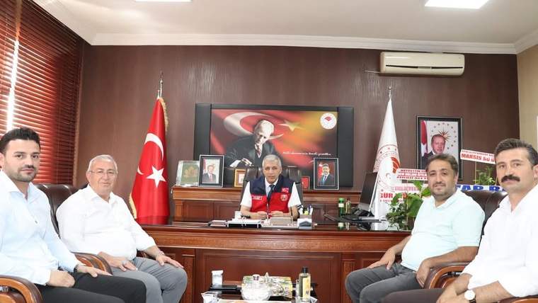 Bir masa etrafında oturan beş kişi, arka planda Türk bayrağı ve Atatürk posteri var.