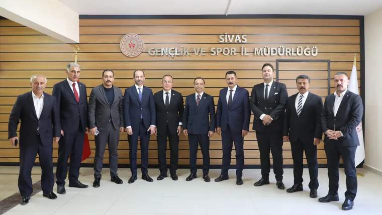 Sivas Gençlik ve Spor İl Müdürlüğü tabelası önünde takım elbiseli bir grup yan yana duruyor.