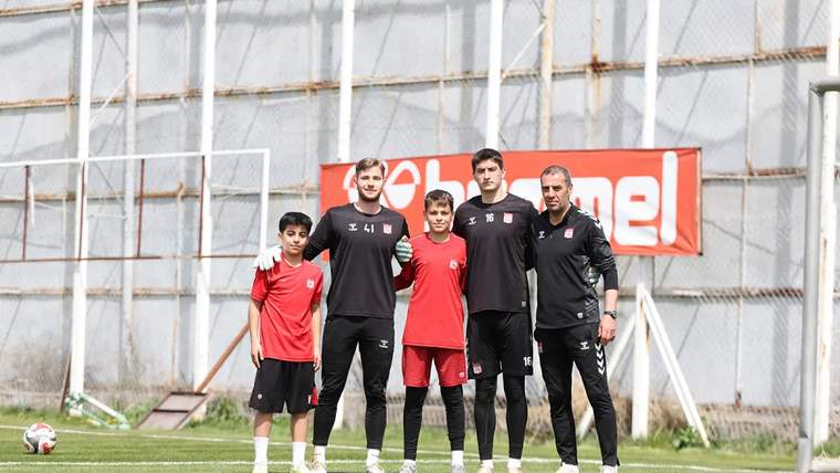 Antrenman sahasında, Sivasspor futbolcuları ve bir çocuk, poz veriyorlar.