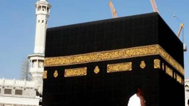 Kabe'nin siyah örtüsü ve yanında bir minare görünmektedir.