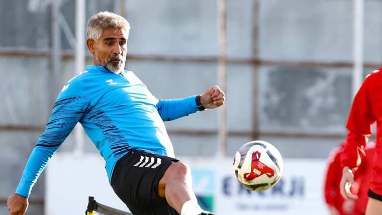 Mavi bir antrenman kıyafeti giymiş bir futbolcu, topa vurarak antrenman yapıyor.