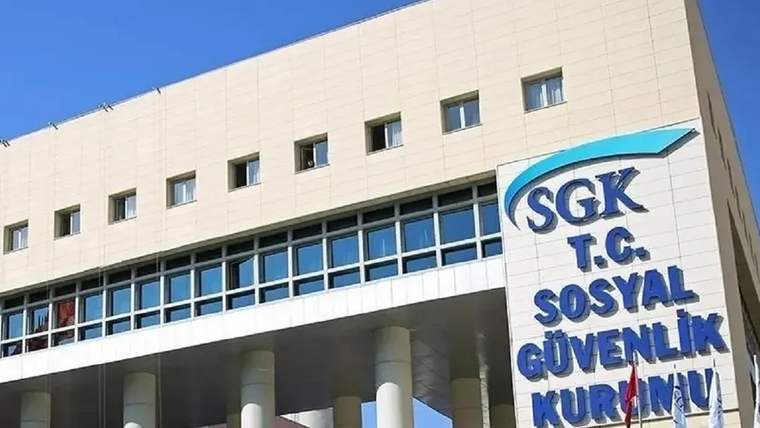 SGK ve T.C. Sosyal Güvenlik Kurumu yazılı tabelanın önünde, pencereli bir kamu binası görülüyor.