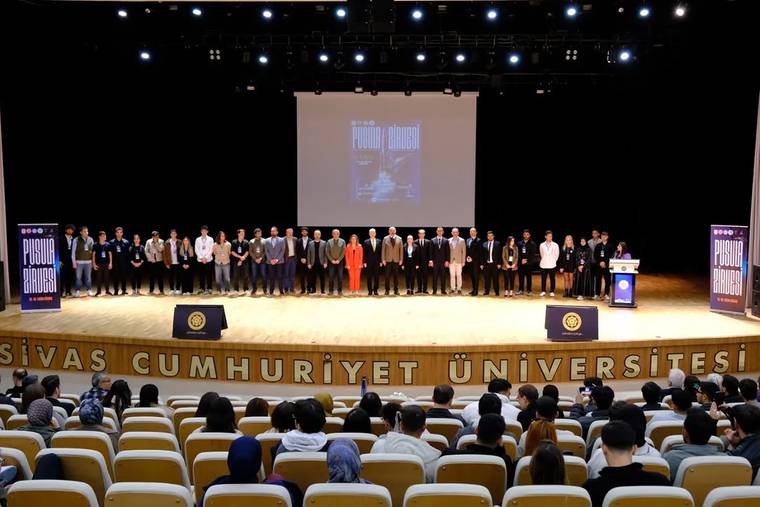 Sivas Cumhuriyet Üniversitesi'nde düzenlenen Pusula Zirvesi'nde katılımcılar sahnede sıralanmış.