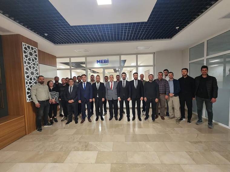 MEBİ yazılı bir alanın girişinde, koridorda yan yana duran kalabalık bir grup görülüyor.