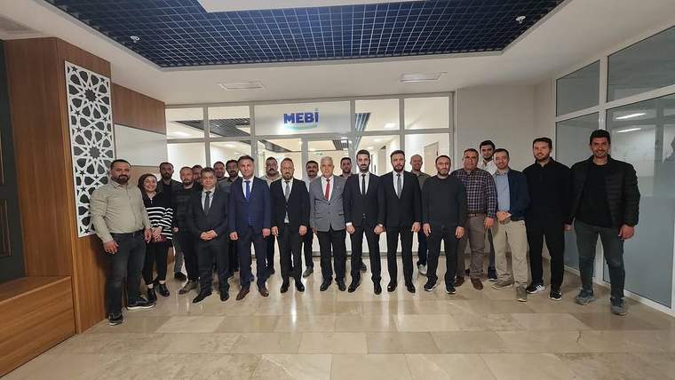 MEBİ yazılı bir alanın girişinde, koridorda yan yana duran kalabalık bir grup görülüyor.