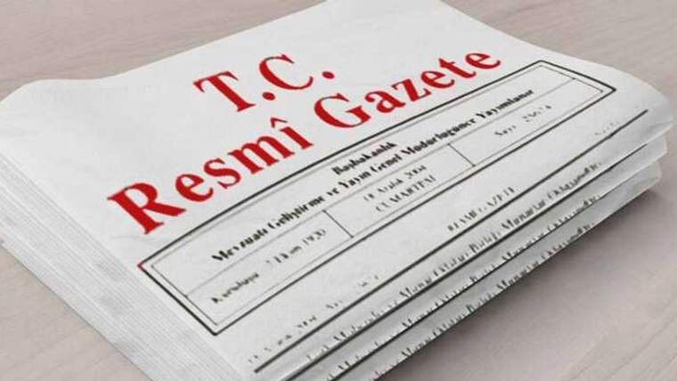 Masa üzerinde, kapağında “T.C. Resmî Gazete” yazan üst üste dizilmiş gazete nüshaları bulunuyor.