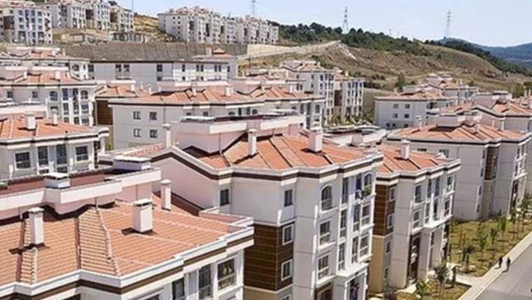 Kırmızı kiremit çatılı, çok katlı apartman blokları yamaçta ve birbirinin önünde sıralanıyor.