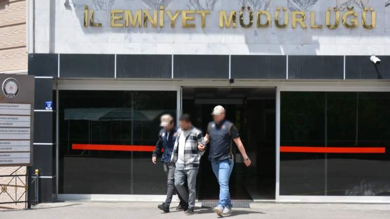 İl Emniyet Müdürlüğü yazılı binanın girişinden iki görevlinin eşlik ettiği bir kişi çıkarılıyor.